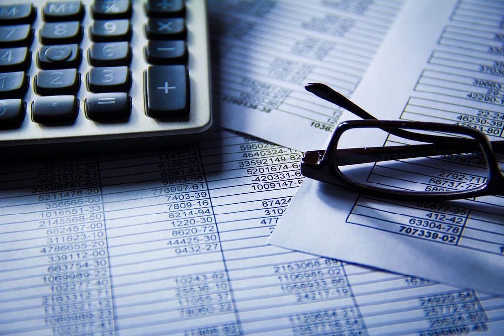 Printed financial spreadsheet with glasses and a calculator